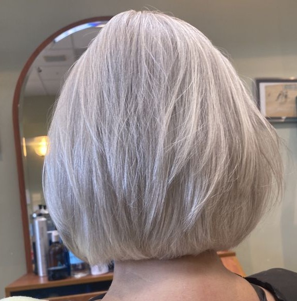 Back view of a sleek silver A-line bob at chin length in the salon chair