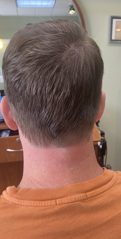 Back of a man's head with a short tapered haircut and clean neckline in the salon
