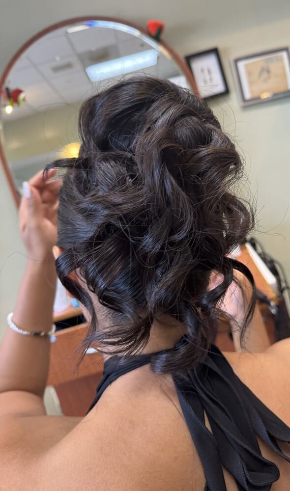 Dark hair pinned up in loose curls, seen from behind in front of a salon mirror